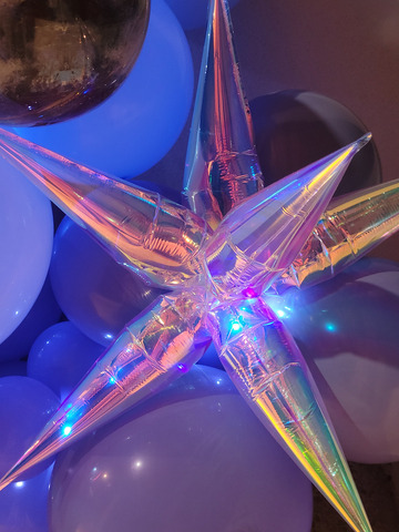Déco ballon starburst et ballon galaxie intégrés dans une décoration en ballons de nuit avec des guirlande lumineuses rappelant les étoiles