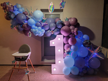 Grande arche de ballons thème galaxie avec un chiffre lumineux géant et guirlandes. Prise de vue de nuit