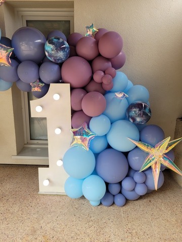 Arche volumineuse de ballons encadrant le côté d'un chiffre lumineux géant pour un anniversaire