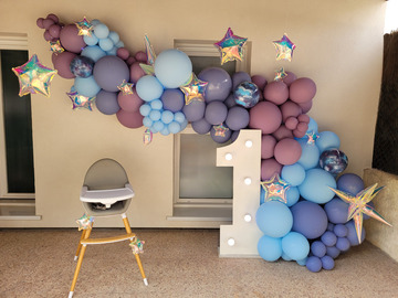 Grande arche de ballons thème galaxie avec un chiffre lumineux géant et étoiles suspendues. Prise de vue de jour