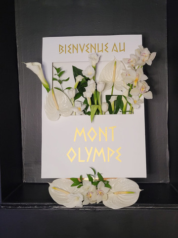 Panneau en bois blanc décoré de fleurs blanches et de textes en vinyle souhaitant la bienvenue