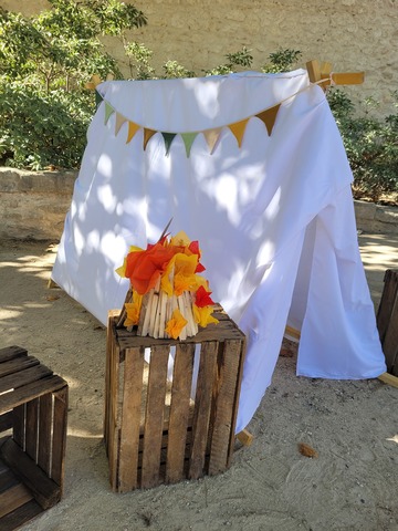 Tente de camp avec fanions colorés et mini feu de camp en bois et papier de soie