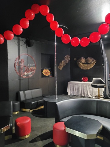 Panneau d'accueil décoré de pampilles, sculptures en mesh doré, compositions florales rouge passion et colliers de perles géantes en ballons