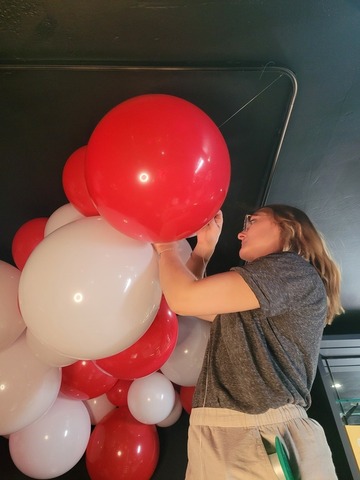 Clémy accrochant les ballons au plafond pour créer une cascade festive sur le thème du cirque